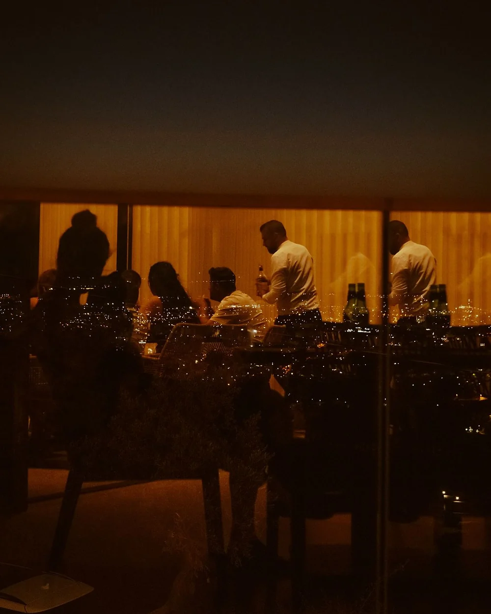 Jantar num terraço ao anoitecer, com a cidade acesa ao fundo