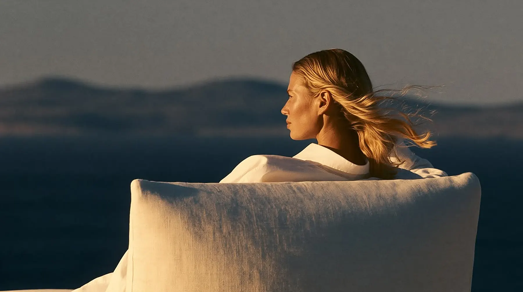 A woman looking out to sea at golden hour
